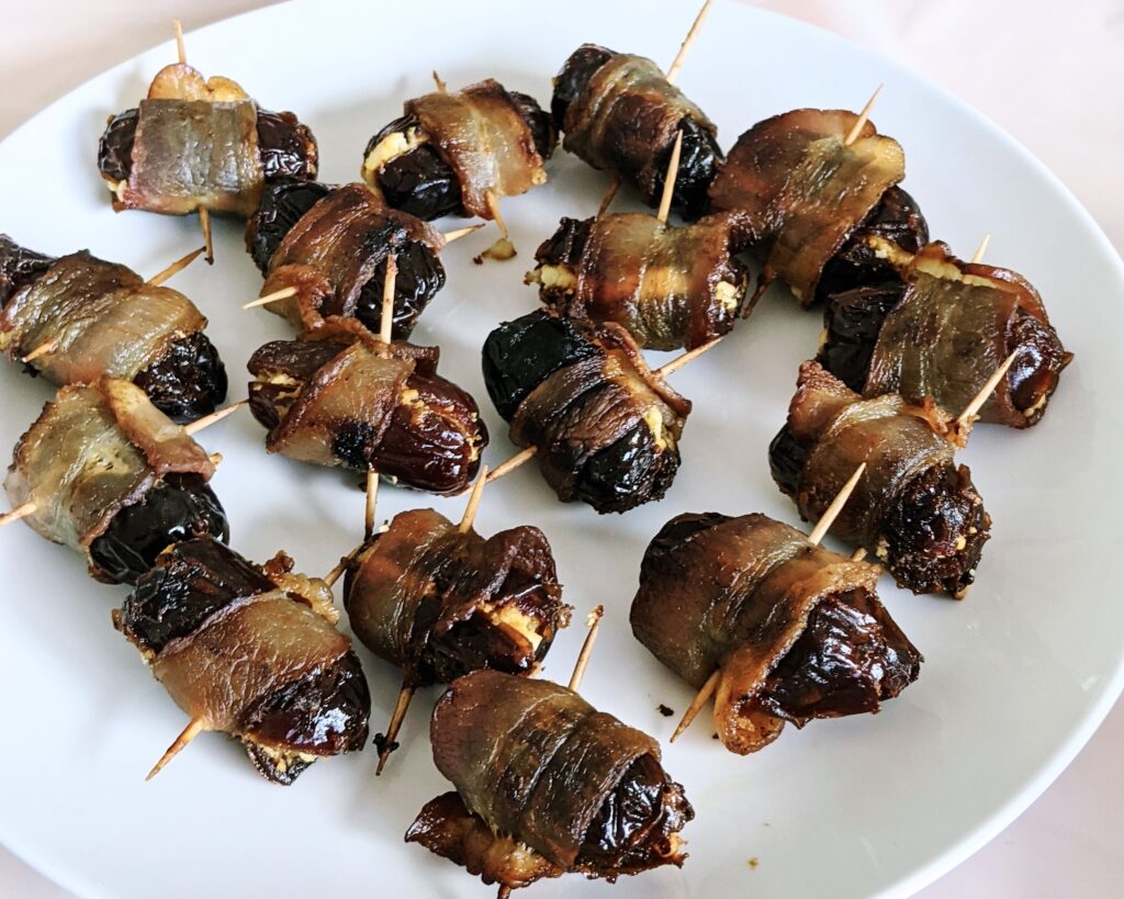 dates with goat cheese wrapped in bacon and a toothpick on a plate