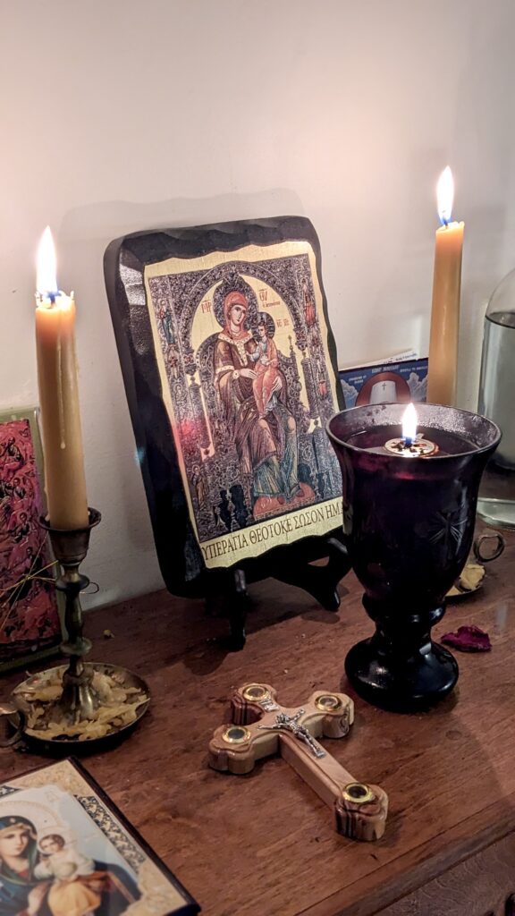 Orthodox Theotokos Icon with candles and cross and vigil lamp in prayer corner