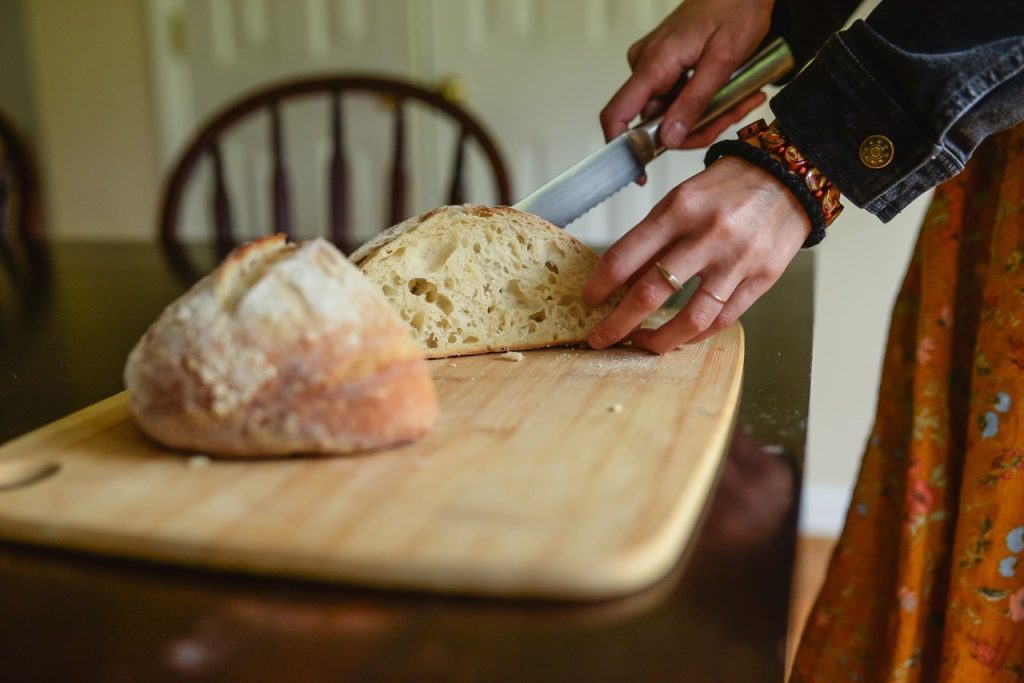 woman cutting sourdough bread on a cutting board