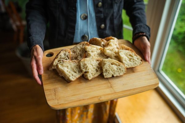 woman holding sourdough bread slices on cutting board