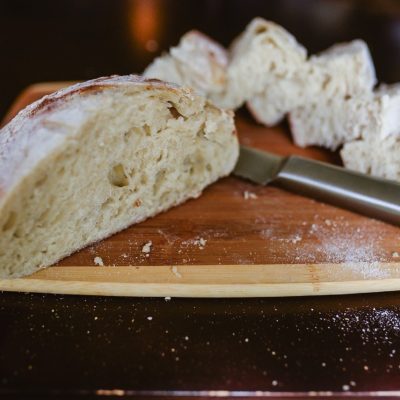 loaf of artisan sourdough bread on cutting board with knife