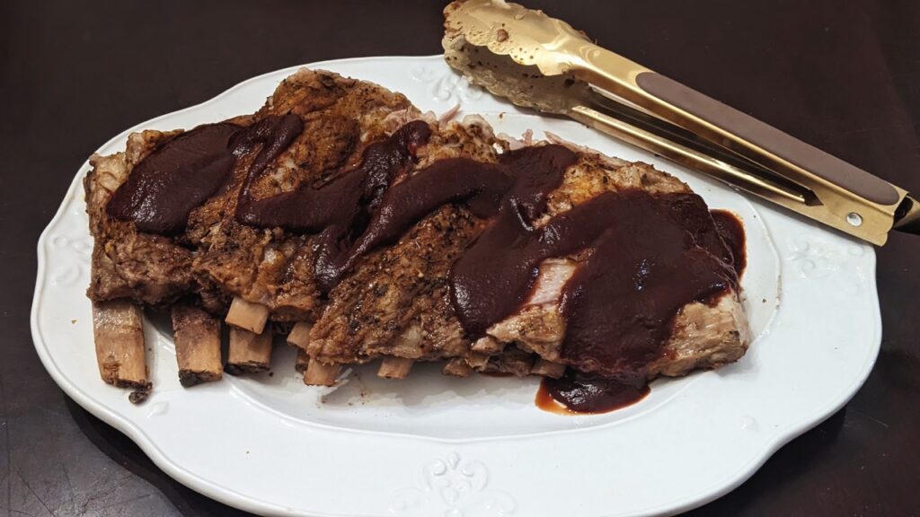 plate of ribs with bbq sauce and gold tongs